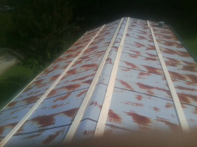 Rusted metal roof panels with new wood purlins before replacement — Storm Damage Roof Repair in Anniston by Roofing Brothers