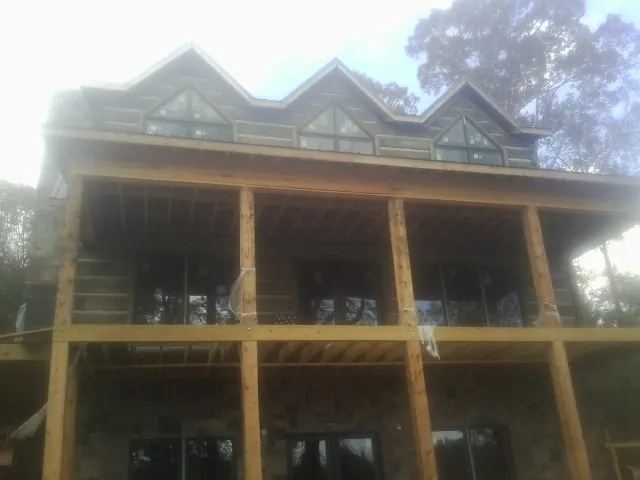 Dormers and porch framing on a large log home under construction — Roof Coating work by our crew in Anniston