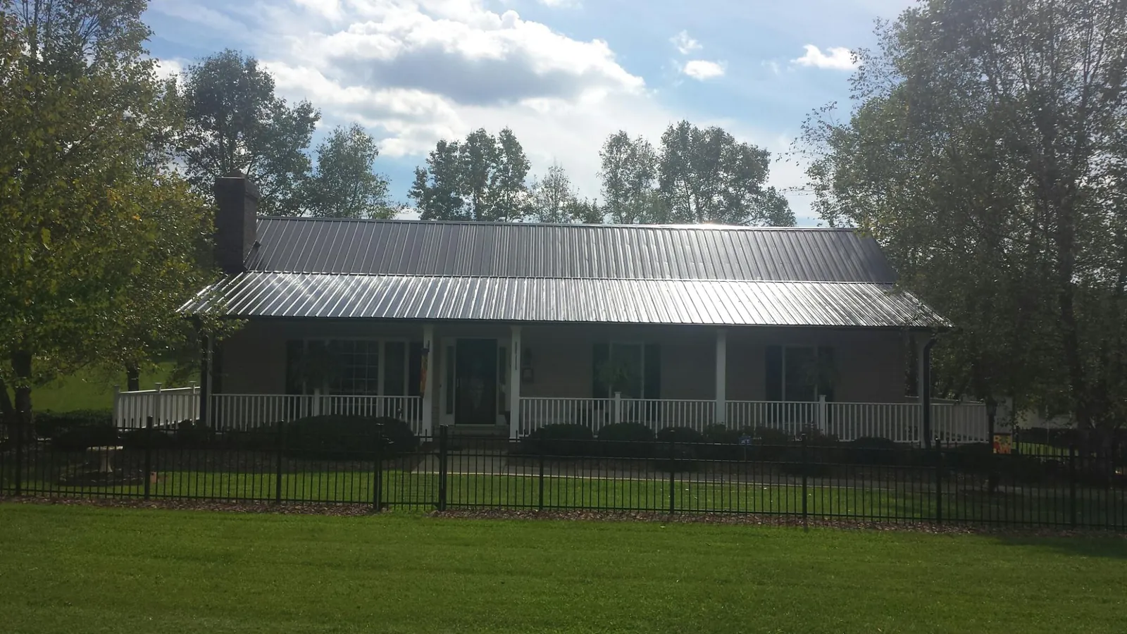Gray metal roof on a brick ranch with a full width front porch — Gutter Guard Installation work by our crew in Anniston